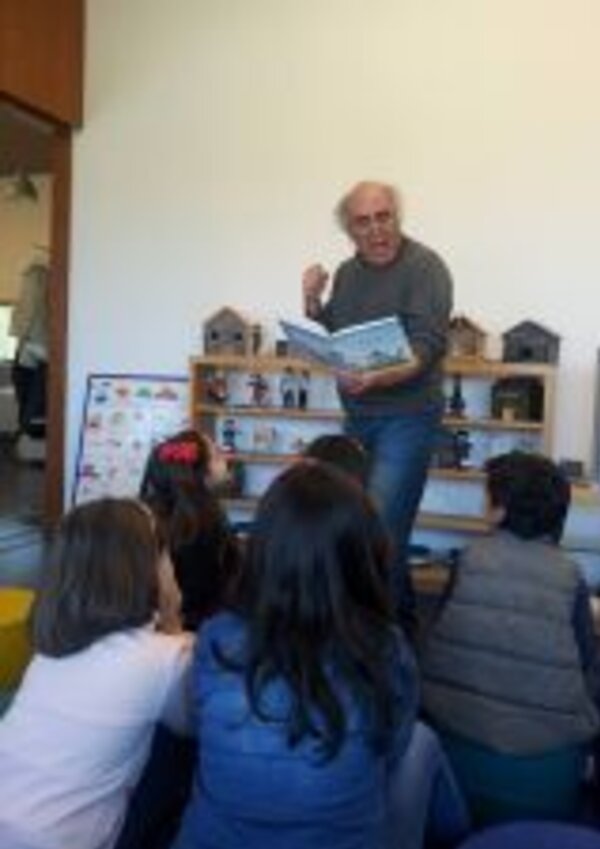 Um contador de histórias lê um livro para crianças sentadas em frente.