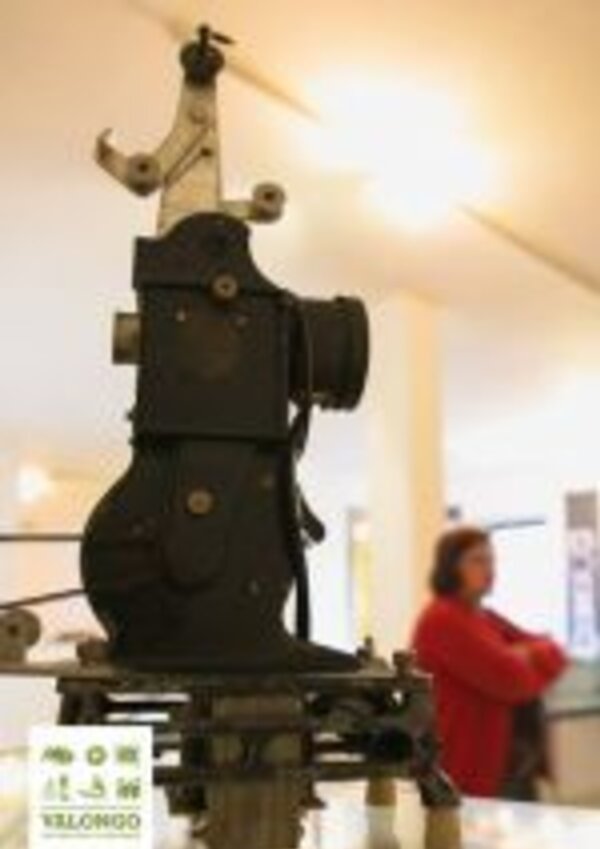 Máquina antiga de costura em exibição, com detalhes mecânicos visíveis.