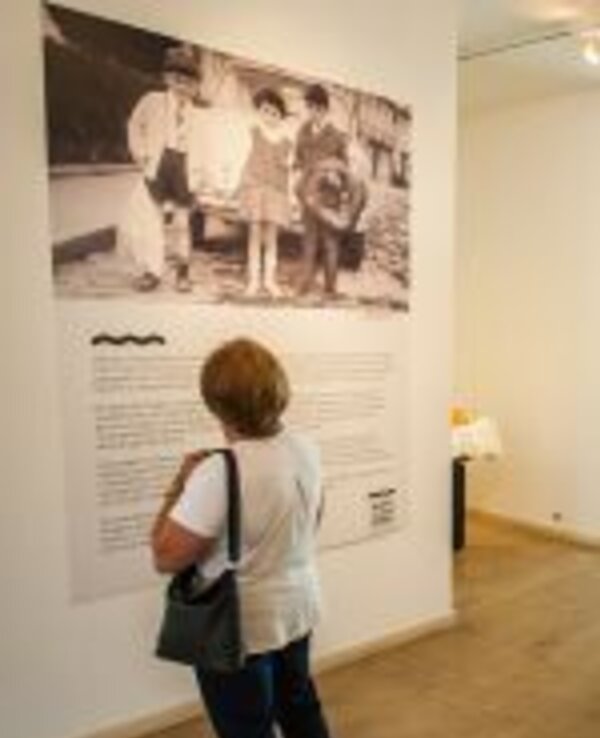 Uma mulher observa uma fotografia antiga numa exposição de arte.