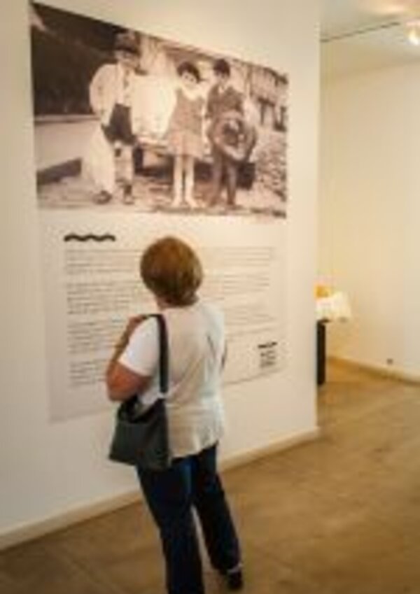 Uma mulher observa uma fotografia antiga numa exposição de arte.