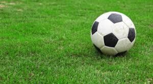 Uma bola de futebol preta e branca sobre um relvado verde.