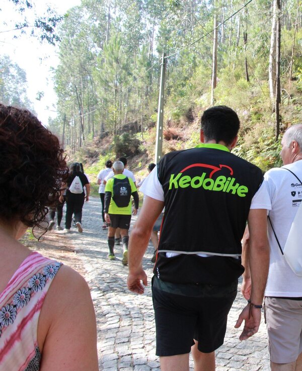 Grupo de pessoas a caminhar numa estrada de terra, rodeados por árvores.