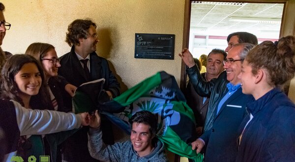Grupo de pessoas a segurar uma bandeira, sorrindo e celebrando.