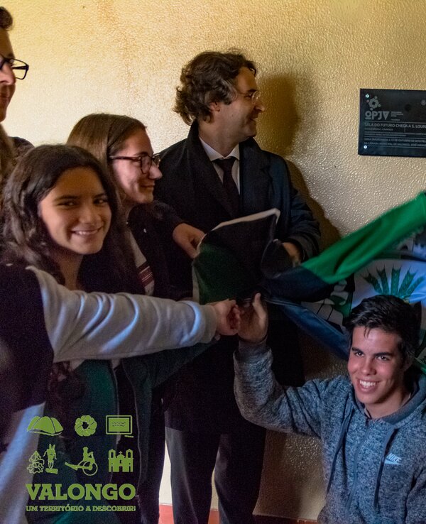 Grupo de pessoas a segurar uma bandeira, sorrindo e celebrando.