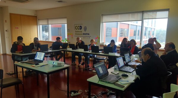 Reunião com várias pessoas a trabalhar em computadores em uma sala iluminada.