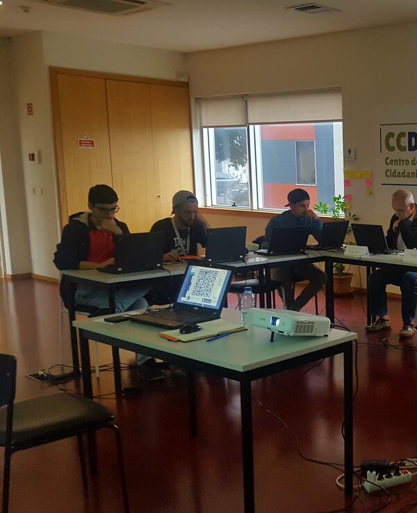 Reunião com várias pessoas a trabalhar em computadores em uma sala iluminada.