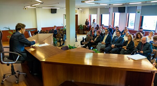 Um orador apresenta-se a uma audiência atenta numa sala de conferências.