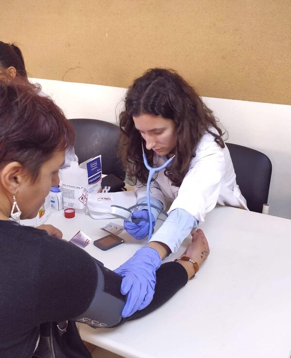 Uma profissional de saúde a medir a pressão arterial de uma paciente.