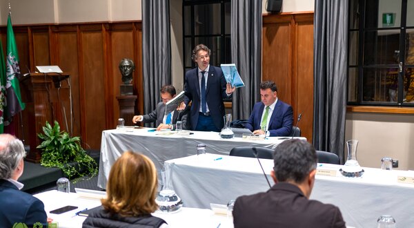 Reunião da câmara municipal com vários membros a discutir documentos.