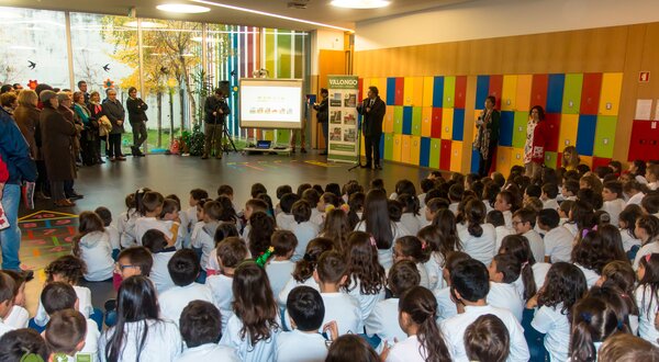 Crianças sentadas em um auditório, assistindo a uma apresentação.