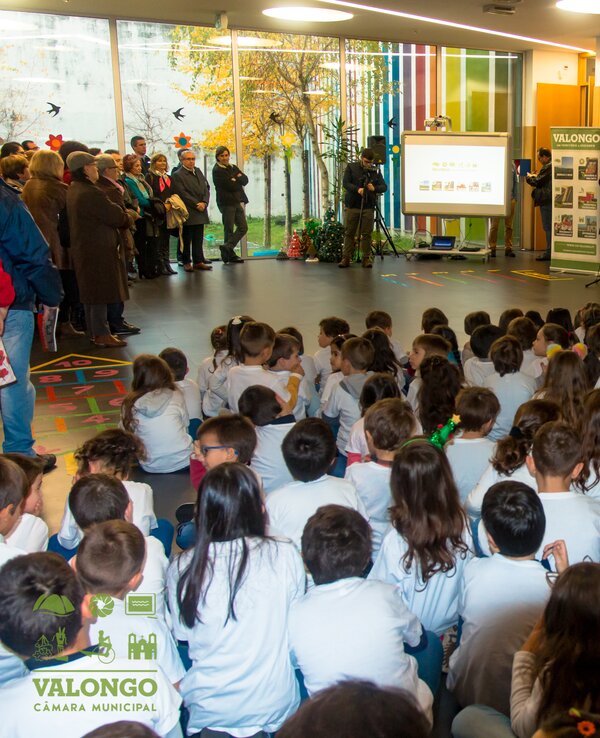 Crianças sentadas em um auditório, assistindo a uma apresentação.