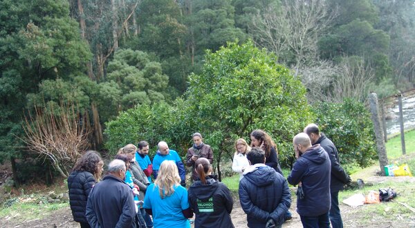 Grupo de pessoas reunidas em círculo, rodeadas por árvores e natureza.