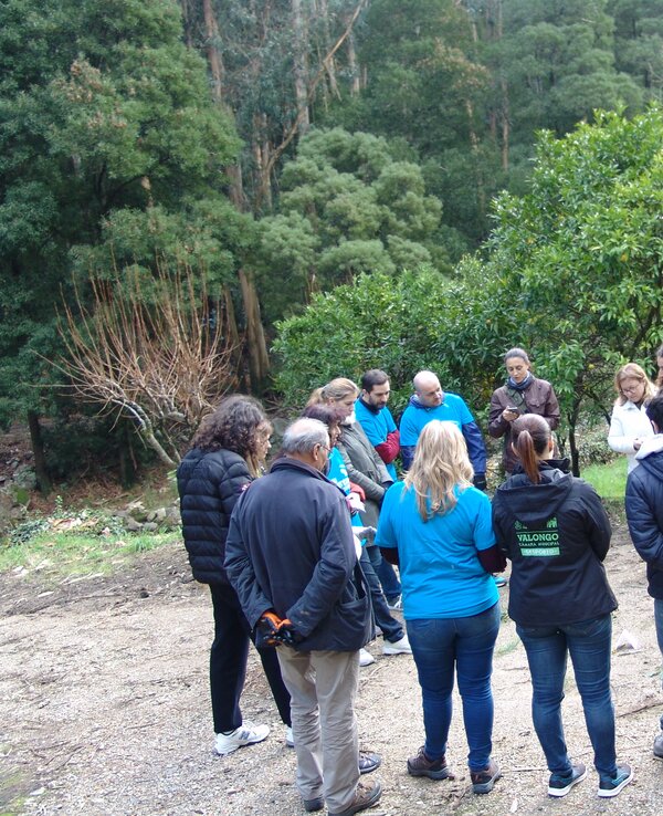 Grupo de pessoas reunidas em círculo, rodeadas por árvores e natureza.