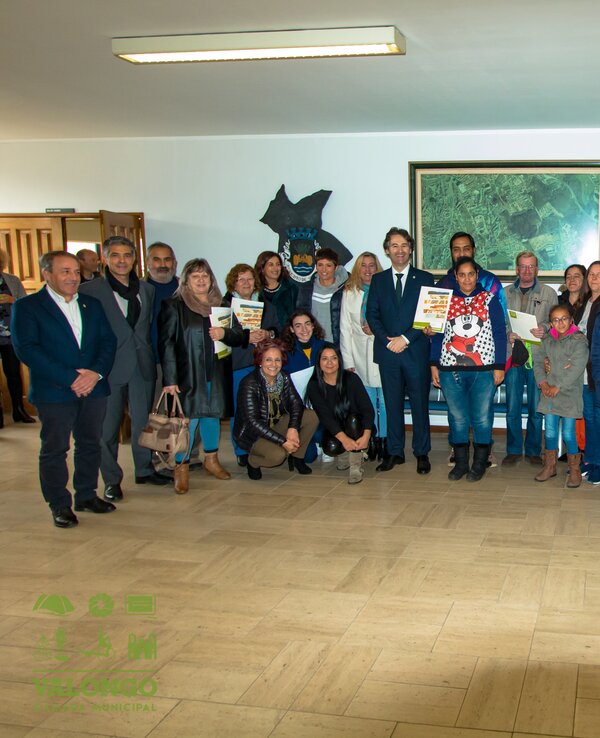 Grupo de pessoas sorridentes reunidas num espaço interior, segurando diplomas.