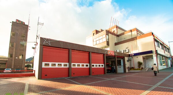 Edifício de bombeiros com portas vermelhas e céu azul ao fundo.