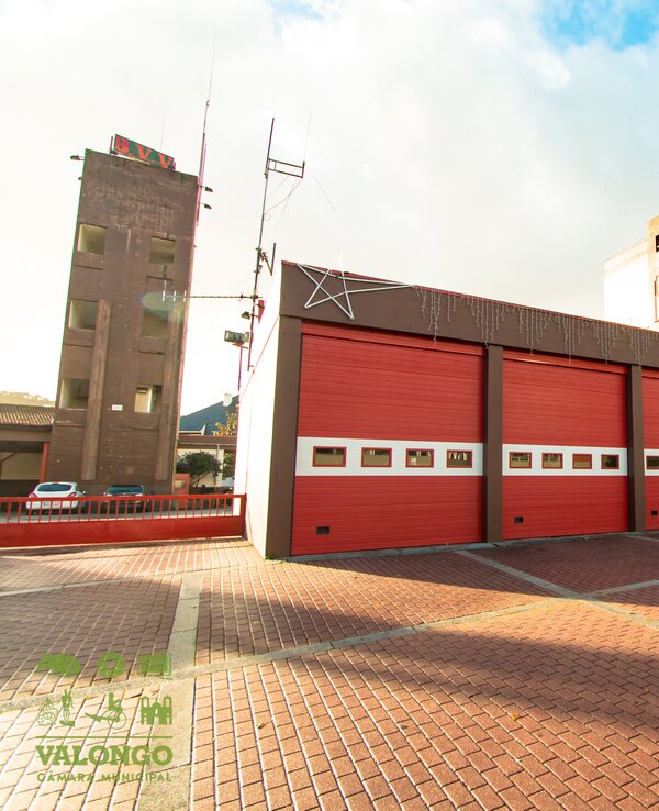 Edifício de bombeiros com portas vermelhas e céu azul ao fundo.