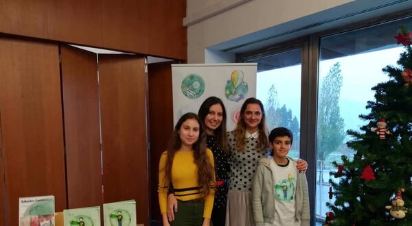 Quatro pessoas posam juntas em frente a uma árvore de Natal decorada.