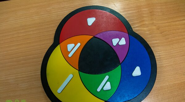 Um jogo de tabuleiro com círculos coloridos e formas brancas.