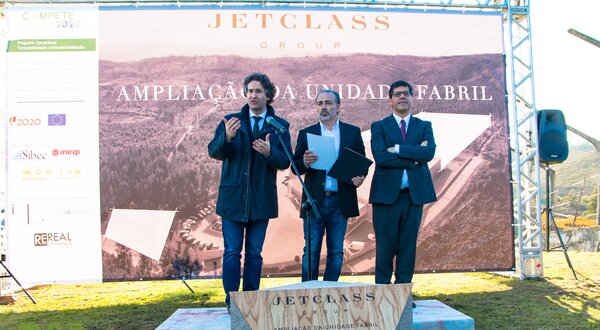Três homens em evento de inauguração, com placa de homenagem ao fundo.