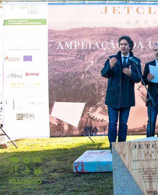 Três homens em evento de inauguração, com placa de homenagem ao fundo.