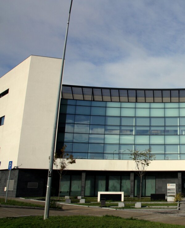 Fachada moderna de um edifício com grandes janelas e pessoas a caminhar.
