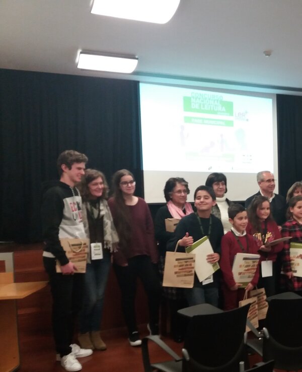 Grupo de crianças e adultos a receber prémios num evento, com diplomas nas mãos.