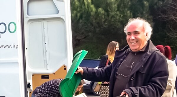 Um homem segura um compostor e um recipiente verde para resíduos orgânicos.