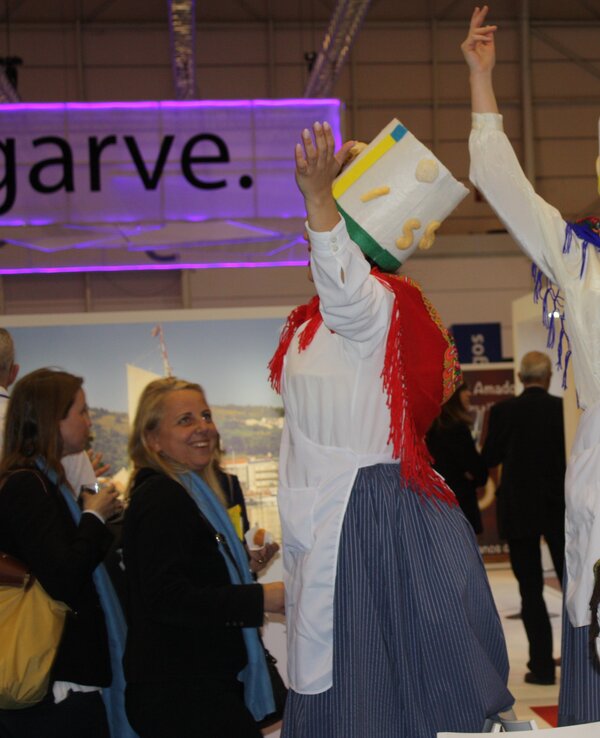 Grupo de pessoas vestidas com trajes tradicionais, a dançar e a segurar pão.