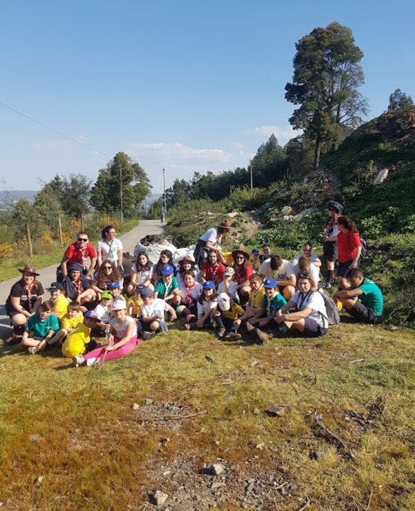 Grupo de crianças e adultos sorridentes numa atividade ao ar livre.