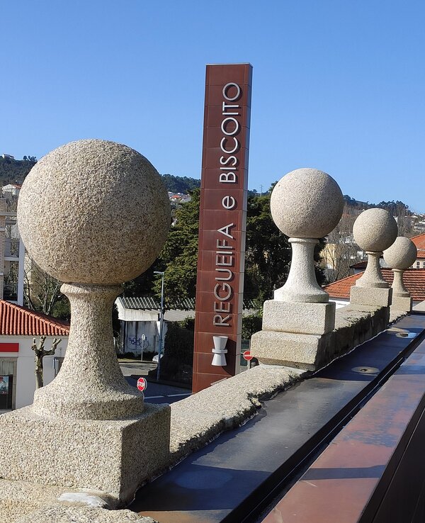 Vista de uma varanda com esferas de pedra e um letreiro de Regueifa e Biscoito.