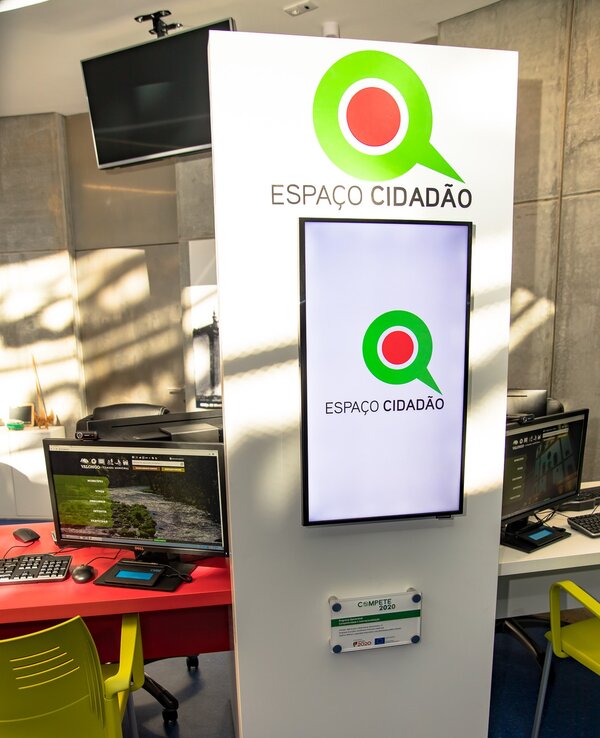 Interior do Espaço Cidadão com computadores e sinalização visível.
