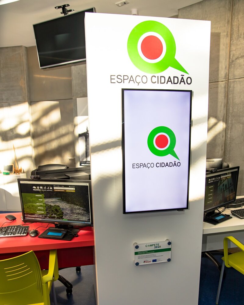 Interior do Espaço Cidadão com computadores e sinalização visível.