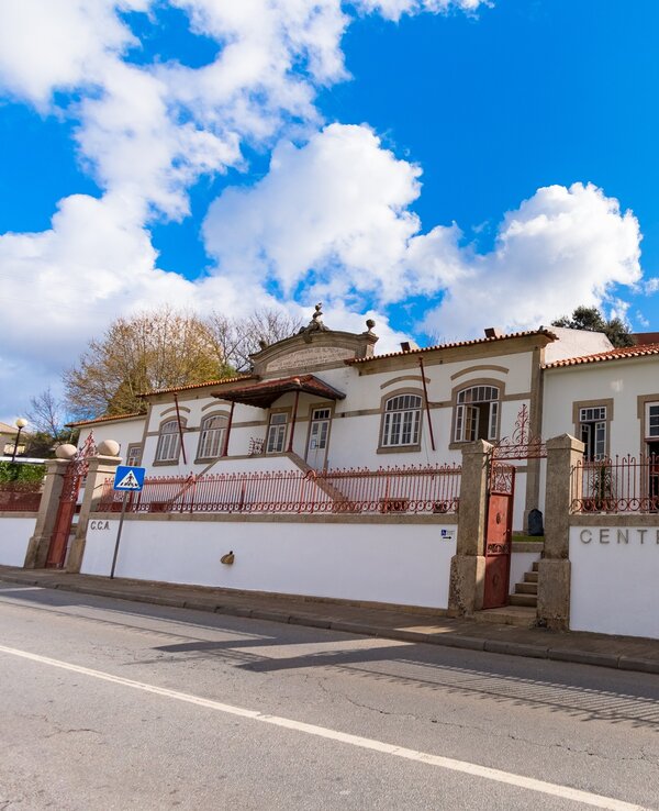 Fachada do Centro Cultural de Alfena, com céu azul e nuvens.