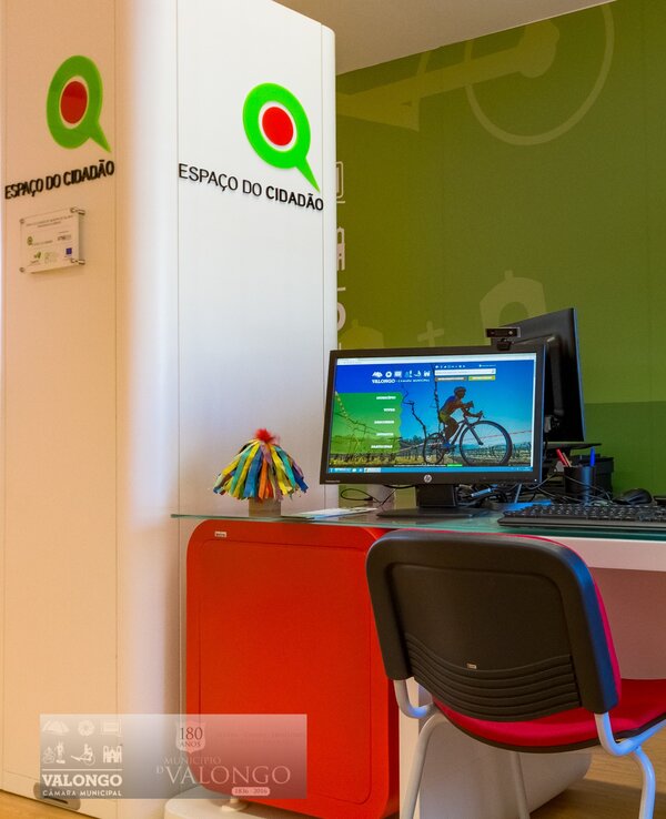 Escritório moderno com computador e cadeira vermelha, decorado com verde.