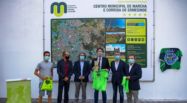Grupo de pessoas a receber camisetas verdes em evento no Centro Municipal de Marcha.