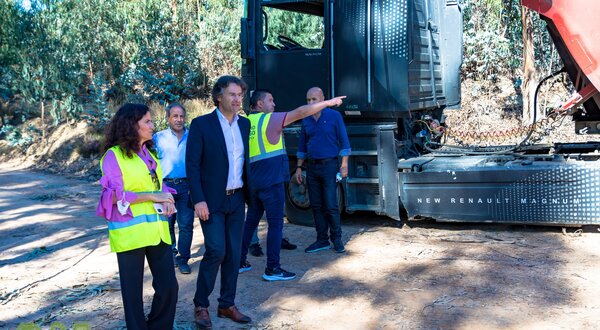 Grupo de pessoas em um local ao ar livre, observando um camião.