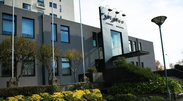 Fachada moderna de um edifício com jardim bem cuidado e flores amarelas.