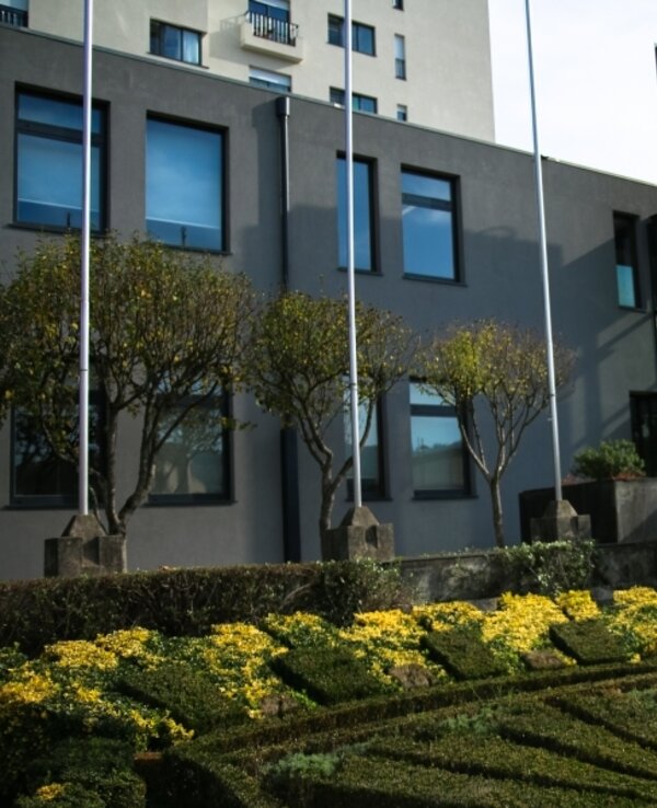 Fachada moderna de um edifício com jardim bem cuidado e flores amarelas.