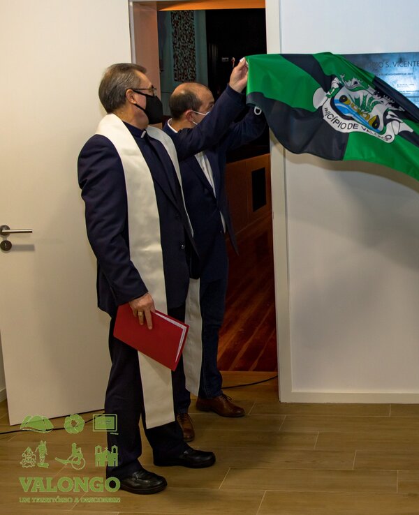 Cerimónia de descerramento de placa com bandeira em ambiente formal.