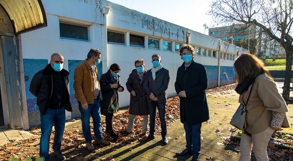 Grupo de pessoas em frente a uma piscina, com folhas secas no chão.