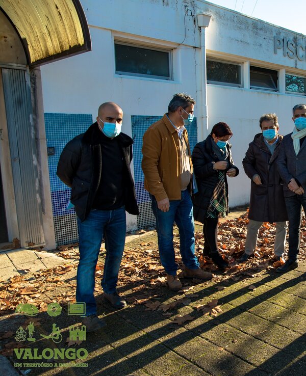 Grupo de pessoas em frente a uma piscina, com folhas secas no chão.