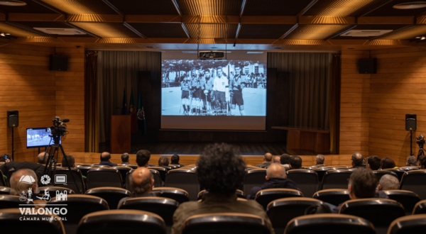 Público sentado em auditório a assistir a uma apresentação em ecrã.