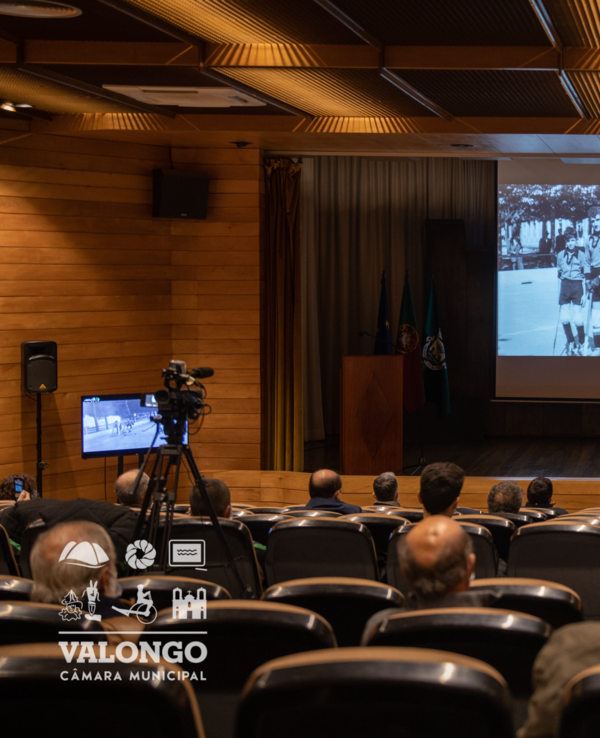Público sentado em auditório a assistir a uma apresentação em ecrã.