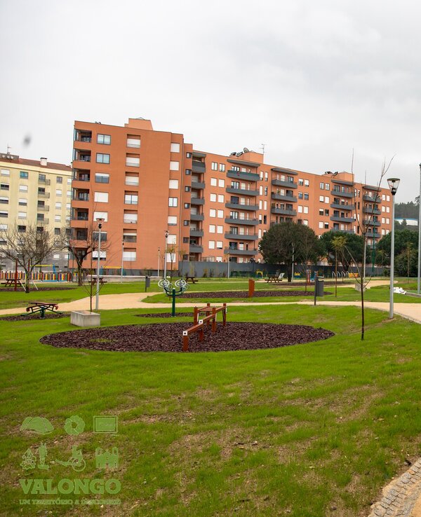 Parque com relvado, campo de futebol e edifícios residenciais ao fundo.