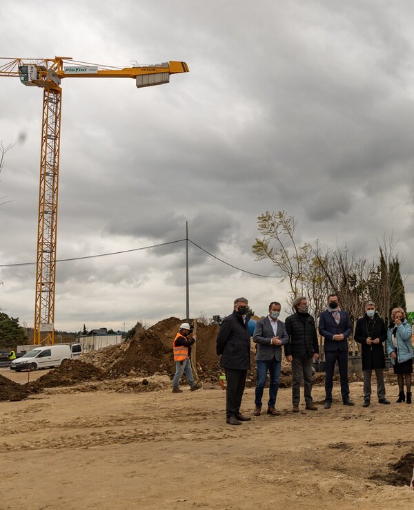 Grupo de pessoas em cerimónia de plantação de árvore, com grua ao fundo.
