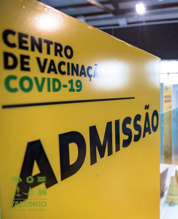 Placa amarela com a palavra 'ADMISSÃO' em um centro de vacinação COVID-19.