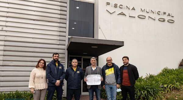 Grupo de pessoas à frente da Piscina Municipal de Valongo, segurando um documento.