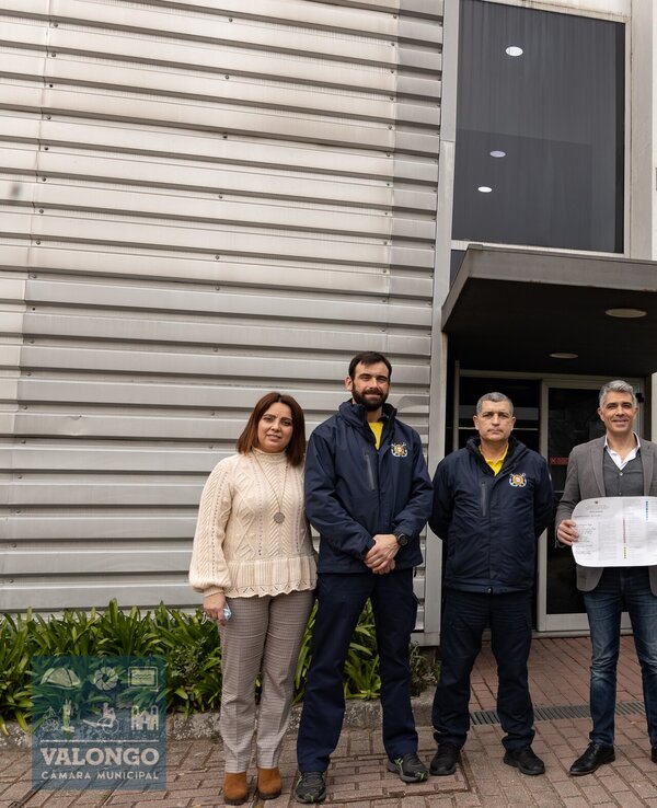 Grupo de pessoas à frente da Piscina Municipal de Valongo, segurando um documento.