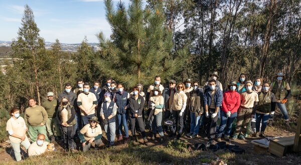Grupo de pessoas em um bosque, todas usando máscaras, posando para a foto.