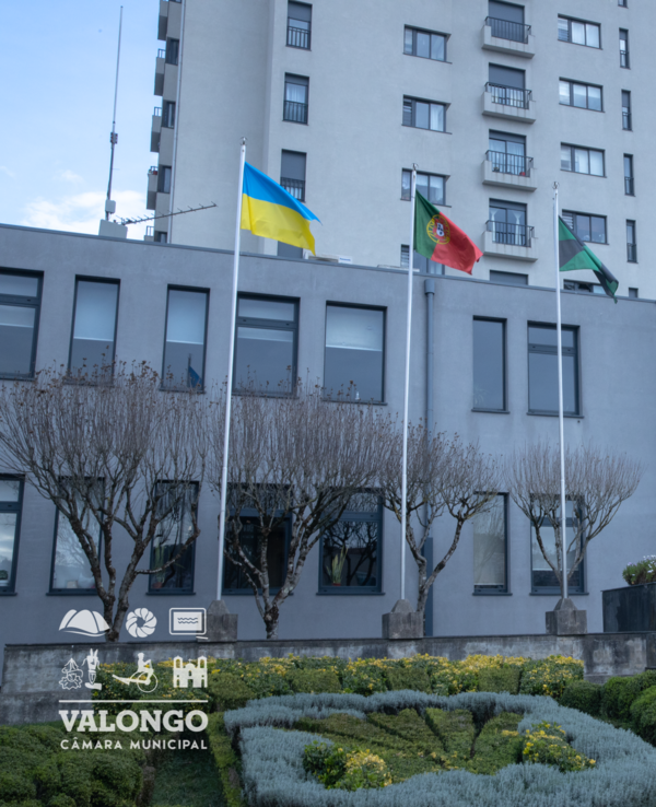 Fachada da Câmara Municipal de Valongo com bandeiras e jardim bem cuidado.